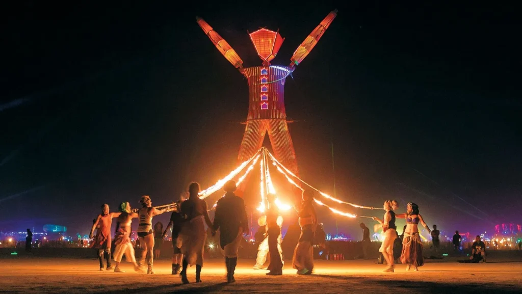 A spectacular mutant vehicle shaped like a dragon breathes fire on the playa at sunset during Burning Man
